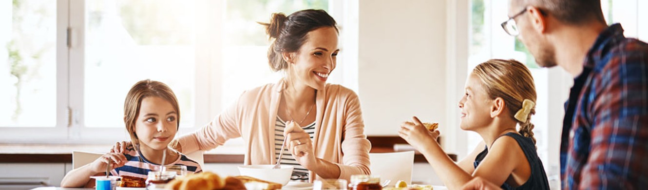 Parents and two kids talking over family dinner